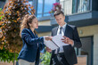 © zinkevych - Client in a black suit scrutinizing the contract, broker assisting him