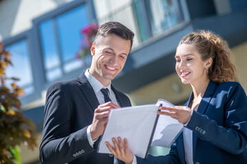 Well-dressed male client signing the documents, female broker looking pleased