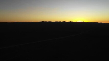 Wall Mural - Aerial footage of an amazing sunset at Atacama Desert mountains. The lights from the sun below the horizon illuminates the sky above the mountains silhouette. An idyllic scenery to view in Chile
