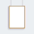 © kaisorn - Wooden frame with poster mockup hanging on gray wall.