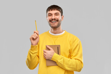 Wall Mural - inspiration, idea and people concept - smiling young man in yellow sweatshirt with diary and pencil over grey background