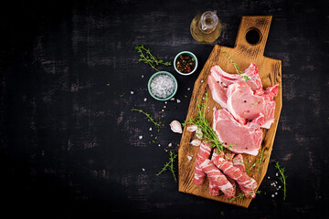 Wall Mural - Raw pork steaks. Different types of raw pork meat and chopped sausages оn the dark table. Top view, overhead, copy space