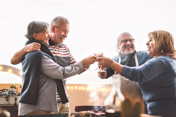 Happy senior friends drinking red wine at barbecue on house patio - Mature people cheering and dining together at bbq party - Food and elderly friendship lifestyle concept