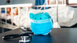 © phoomrat - piggy bank in hospital in protective face mask, hand alcohol gel, stethoscope, thermometer, patient bed background. saving money for health care concept