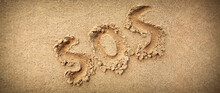 SOS Abbreviation Written On A Wide Sand Background.