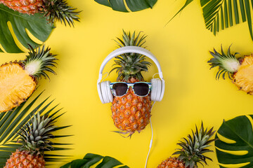 Sticker - Funny pineapple wearing white headphone, listen music, isolated on yellow background with tropical palm leaves, top view, flat lay design concept.