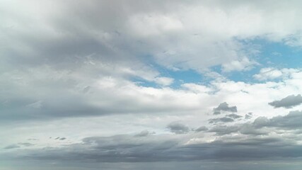 Wall Mural - Time lapse of layers of fluffy white and gray clouds floating beneath a bright blue sky during the day. 