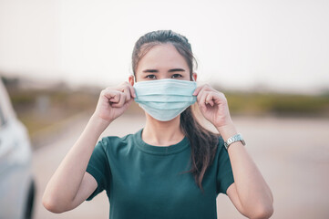 Asian women use surgical mask or face mask at car parked road outdoor