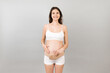 © sosiukin - Close up of pregnant woman in underwear wearing elastic pregnancy bandage to make the pain go away at yellow background with copy space. Orthopedic abdominal support belt concept