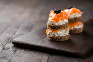 Smoked salmon with creamy cottage cheese and black caviar. Catering finger food, snack, mini canapes.