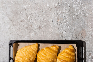 Wall Mural - top view of baked delicious croissants on baking tray on concrete grey surface