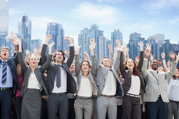 Business people cheering with arms raised in front of skyline