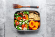 © Westend61 - Lunch box with rocket salad with colored tomatoes, mozzarella and nuts, crispbread and apricots, wooden fork on concrete surface