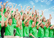 Crowd in green t-shirts cheering with arms raised