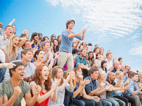 Fotomural Man standing and clapping among cheering crowd