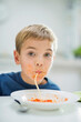 © Tom Merton/KOTO - Boy slurping spaghetti at table