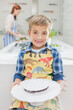 © Tom Merton/KOTO - Boy covered in flour holding cake in kitchen