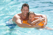 Father And Daughter Relaxing In Swimming Pool