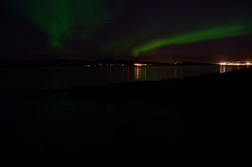 aurora borealis over cold fjord and mountain in autumn