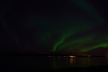 aurora borealis over cold fjord and mountain in autumn