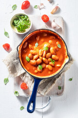 Baked beans made of fresh tomatoes on white table