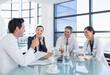 © Chris Ryan/KOTO - Doctors and business people talking in meeting