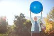 © Paul Bradbury/KOTO - Senior woman holding fitness ball in park