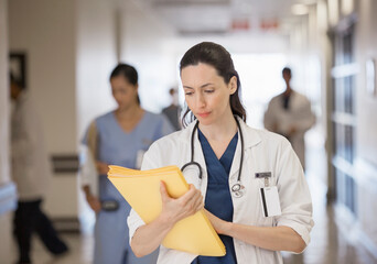 Doctor looking down at folder in hospital corridor