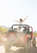 © Martin Barraud/KOTO - Woman cheering in sport utility vehicle on dirt road