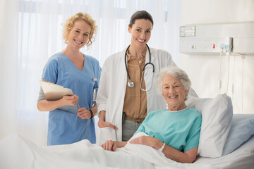 Wall Mural - Doctor, nurse and senior patient smiling in hospital room