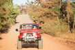 © Martin Barraud/KOTO - Couple driving sport utility vehicle on dirt road