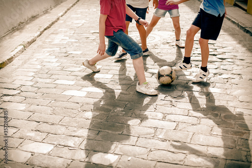 Fotomural Children playing with soccer ball on cobblestone street