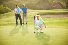 Senior Friends Playing Golf On Course