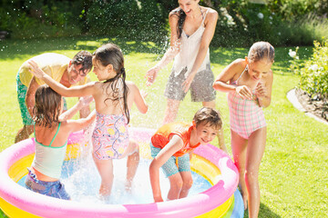 Family playing in paddling pool in backyard