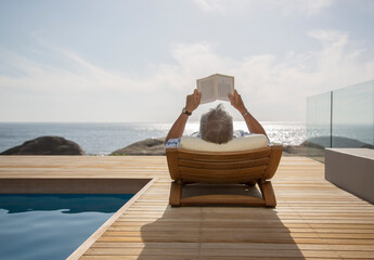 Wall Mural - Older man reading by pool