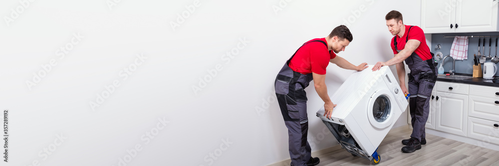 Young Male Mover Carrying Home Appliances In Kitchen