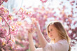Woman photographing pink blossoms on tree