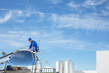 Worker on top of stainless steel milk tanker