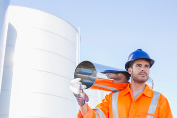 Worker carrying stainless steel tube near silage storage tower