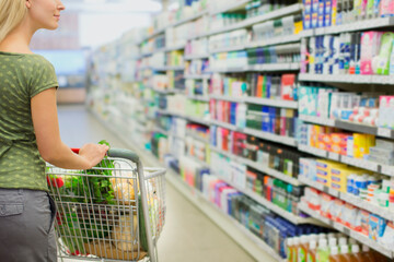 Canvas Print - Woman pushing full shopping cart in grocery store