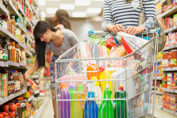 Wall Mural - Woman pushing full shopping cart in grocery store