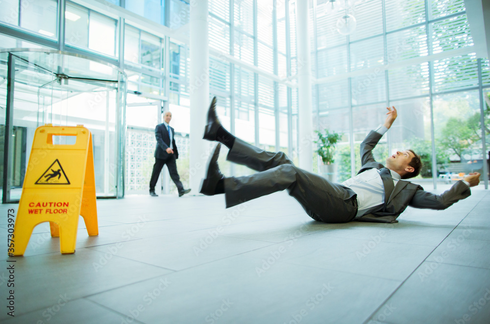 Businessman slipping on floor of office building - obrazy, fototapety, plakaty 