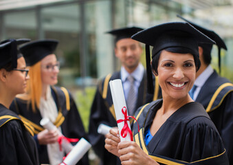 Student in cap and gown smiling with colleges