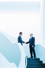 Businessmen shaking hands on stairs of office building