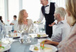 © Dan Dalton/KOTO - Waiter serving fancy dish to woman sitting at restaurant table