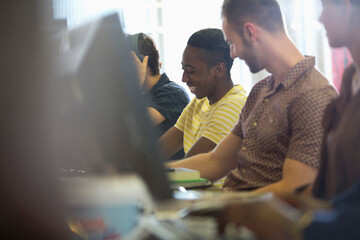 Wall Mural - University students talking and studying on computers in classroom