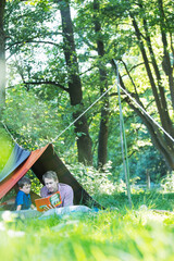 Wall Mural - Father and son reading in camping tent