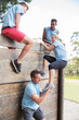© Sam Edwards/KOTO - Teammates helping woman over wall on boot camp obstacle course