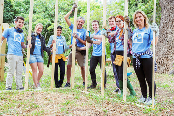 Portrait smiling volunteers holding construction frame at construction site