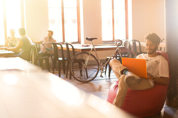 Wall Mural - Casual businessman working at laptop in bean bag chair